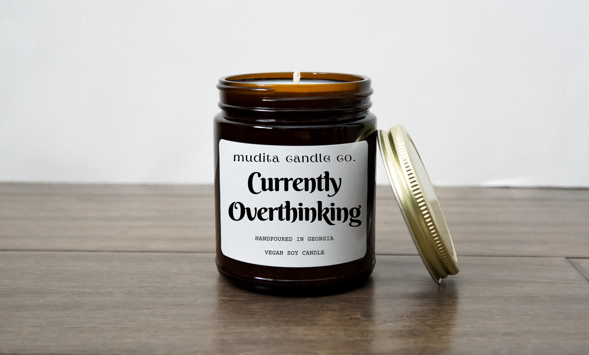 Currently Overthinking candle in a 9oz amber glass jar with a gold metal lid, showcasing its elegant design and soothing aroma.