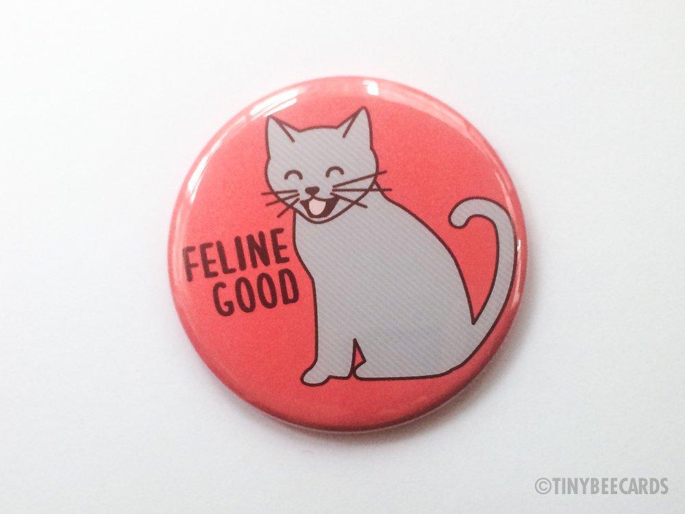 Cute cat button featuring a happy cat and the pun 'Feline Good!' in hot pink color.