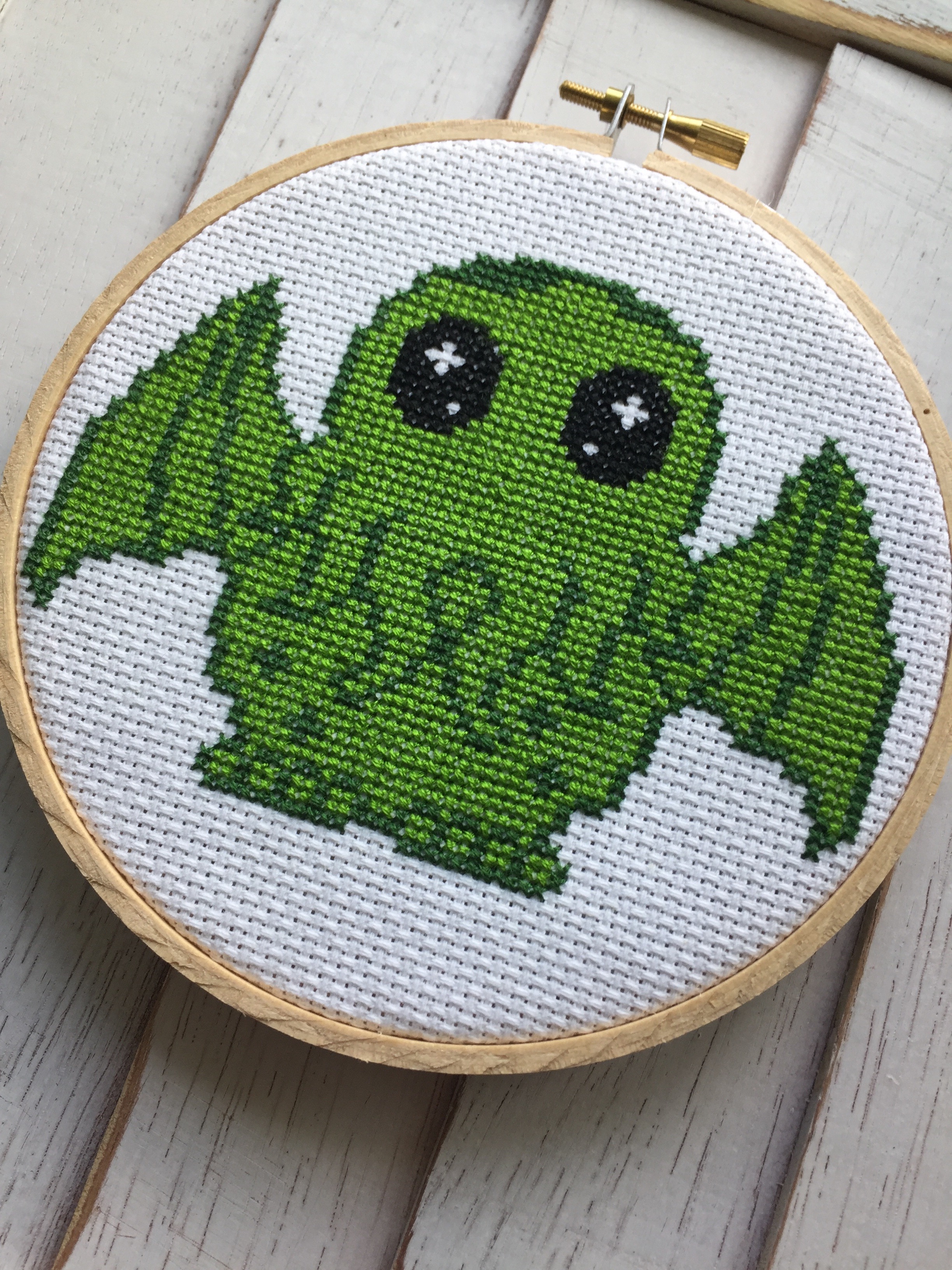 A colorful Cute Cthulhu counted cross stitch kit featuring a 5-inch design, complete with threads, fabric, needle, and wood hoop.