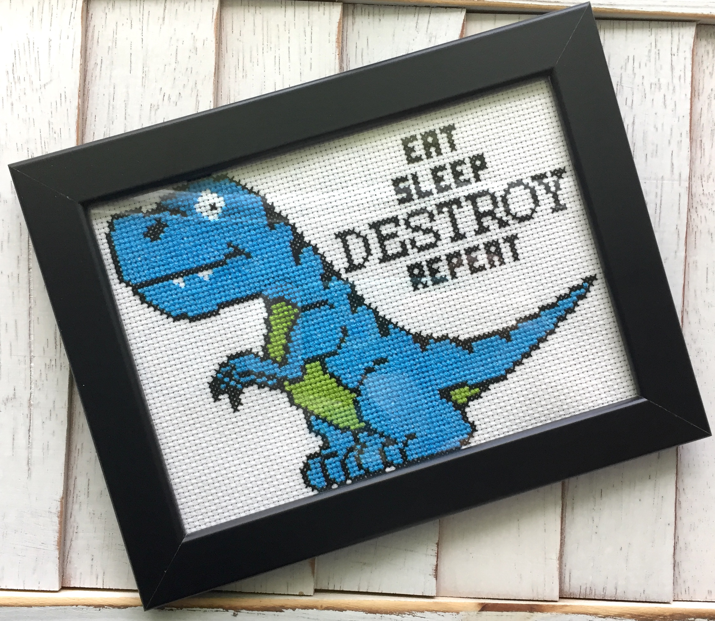 Dinosaur Destroy Counted Cross Stitch DIY Kit featuring a cute T-rex design with the phrase 'Eat Sleep Destroy Repeat', includes all necessary materials.