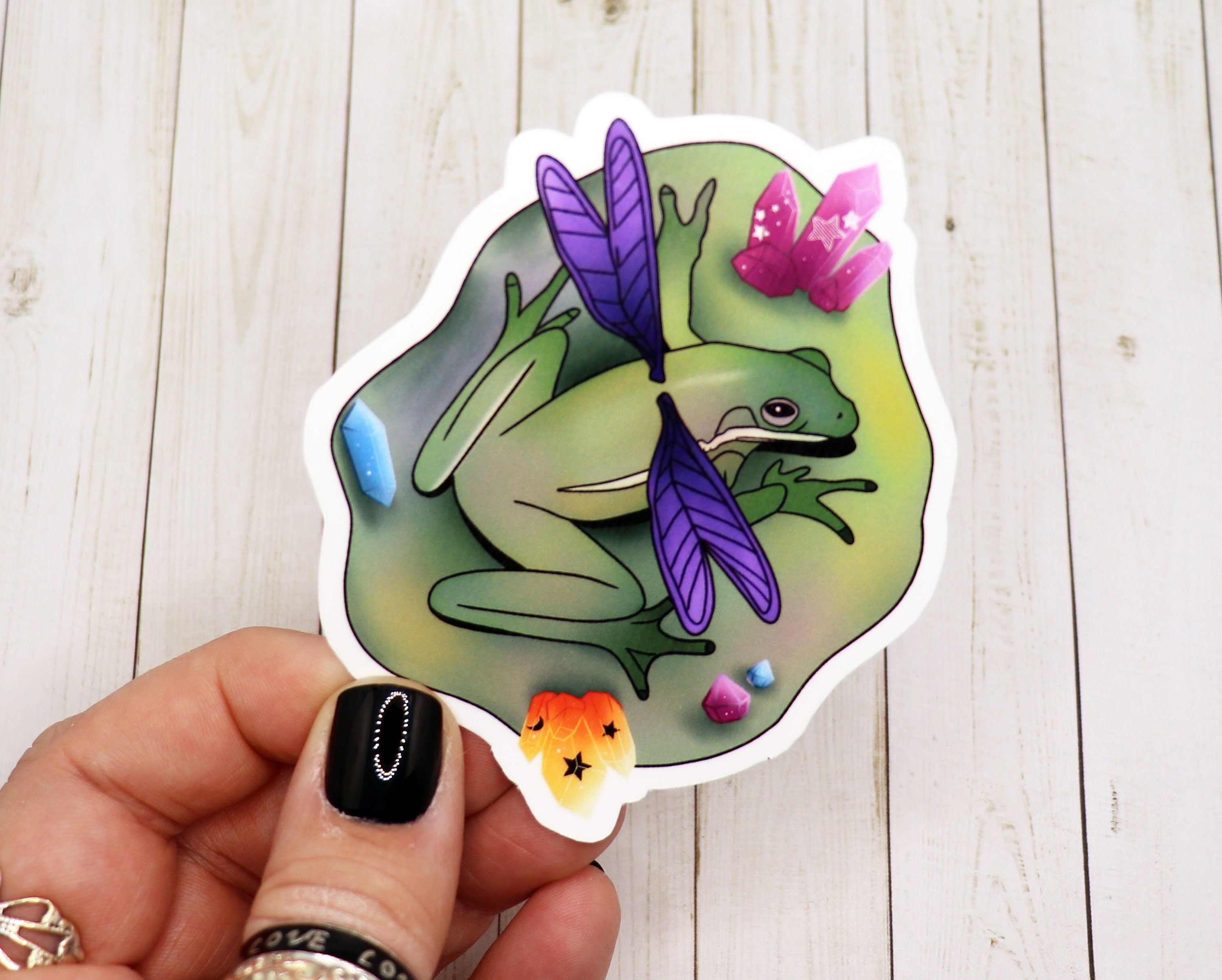 A vibrant Frog Fairy sitting on a lily pad, designed as a sticker, showcasing intricate details and colors.