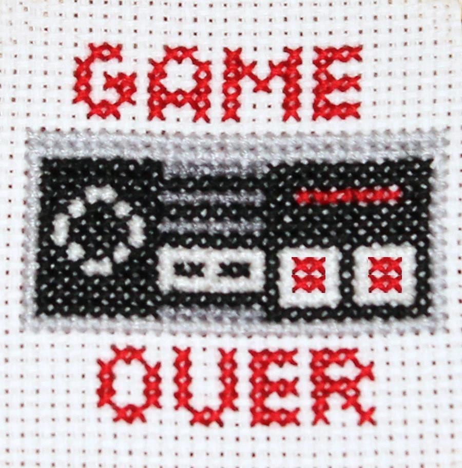 Game Over Controller Counted Cross Stitch DIY Kit featuring a vintage Nintendo controller design with black Aida fabric and colorful DMC threads.
