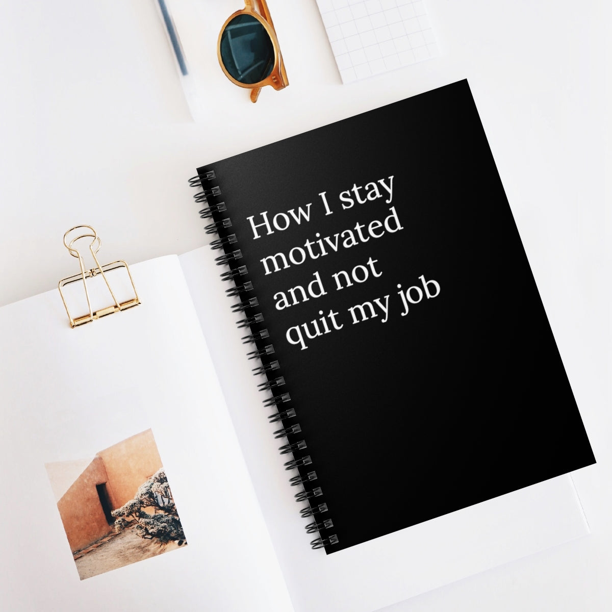 A humorous spiral notebook titled 'How I Stay Motivated and Not Quit My Job' featuring a funny design, ideal for office use.