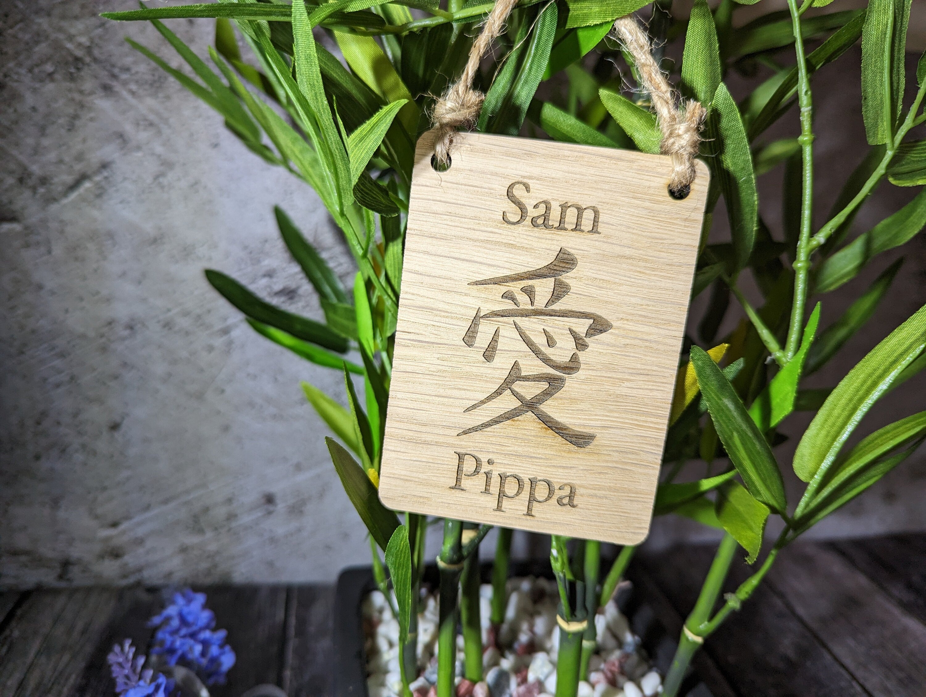 Personalised wooden Japanese sign with engraved names and characters, hanging with rustic jute string.
