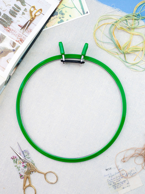 Nurge Large Spring Metal Embroidery Hoop in deep green, showcasing its two-part design with a plastic outer ring and flexible metal inner ring.