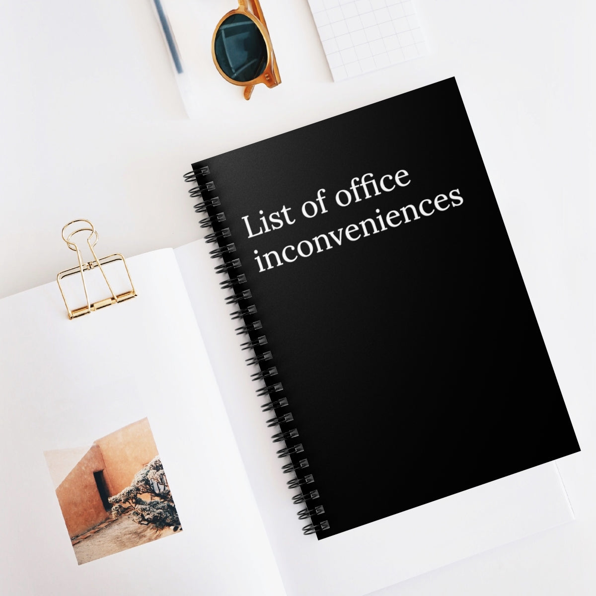 A humorous spiral notebook titled 'List Of Office Inconveniences', featuring ruled line pages and a fun design, perfect for office use.