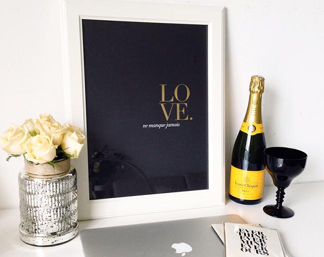 Art print featuring 'Love Never Fails' in French with gold foil accents on colored stock, size 30x40cm.