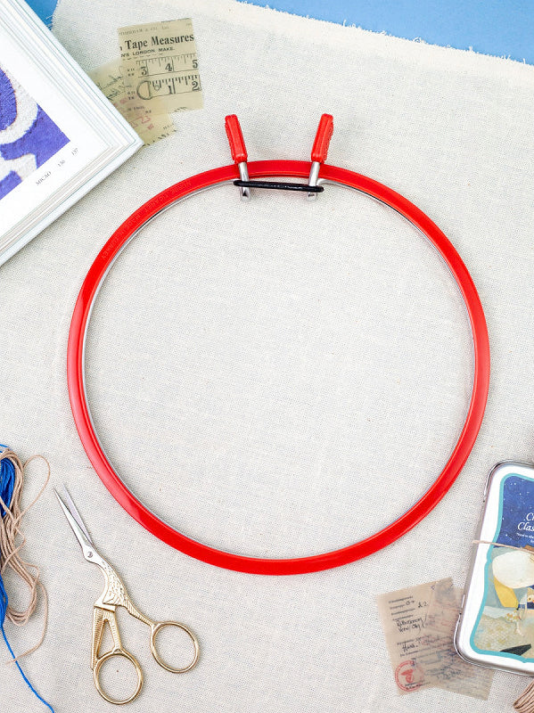 Nurge Medium Spring Metal Embroidery Hoop in Deep Red, showcasing its sleek design and spring tension mechanism.