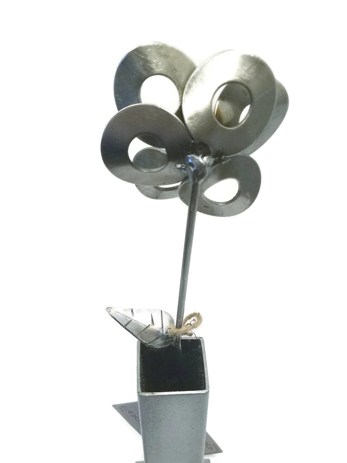 Handcrafted metal flower made from recycled steel, displayed in a matching steel vase, showcasing unique design and craftsmanship.