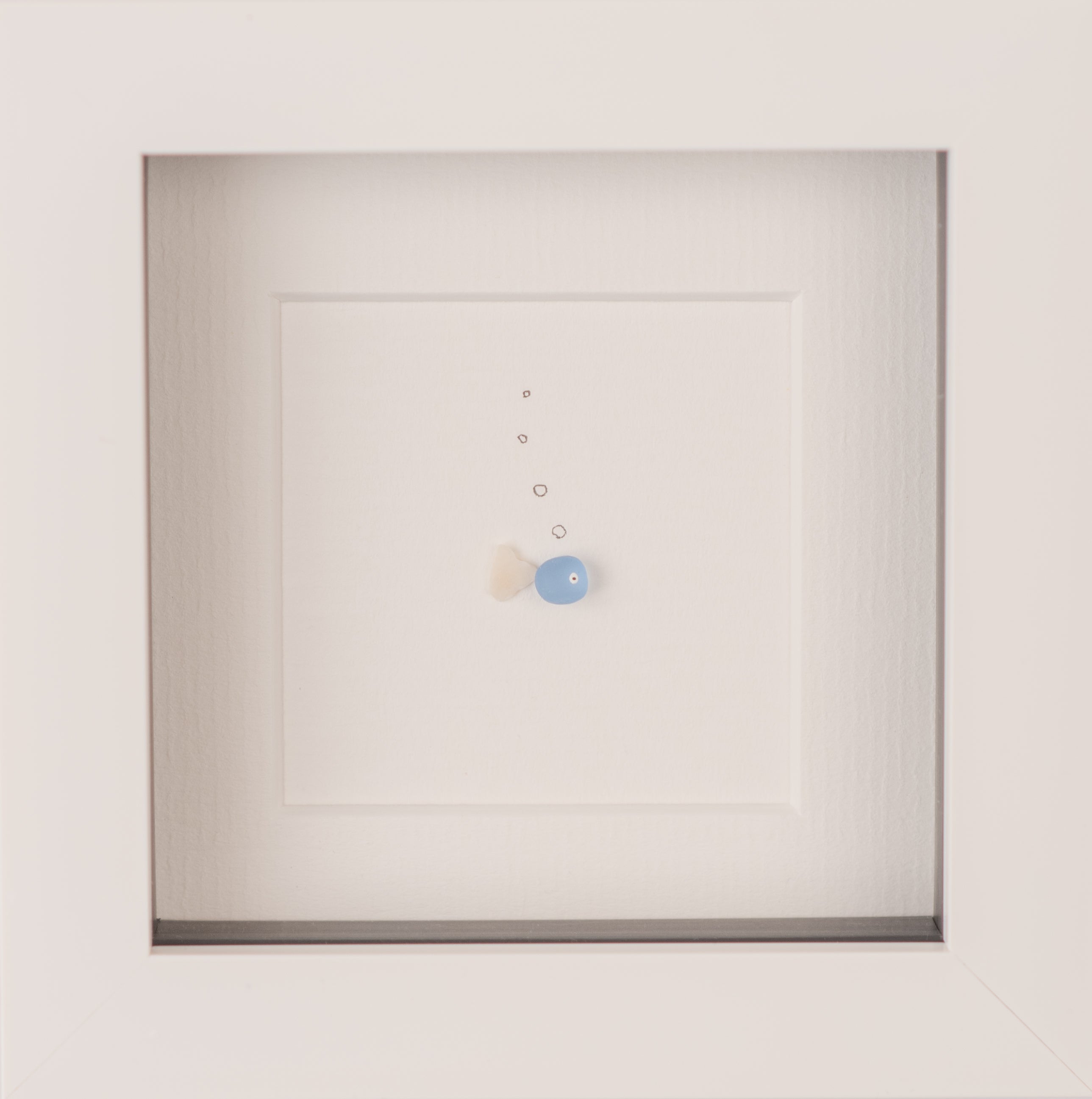 A colorful Mini Fish artwork made from sea glass, framed in a sleek black frame, showcasing its unique design inspired by nature.