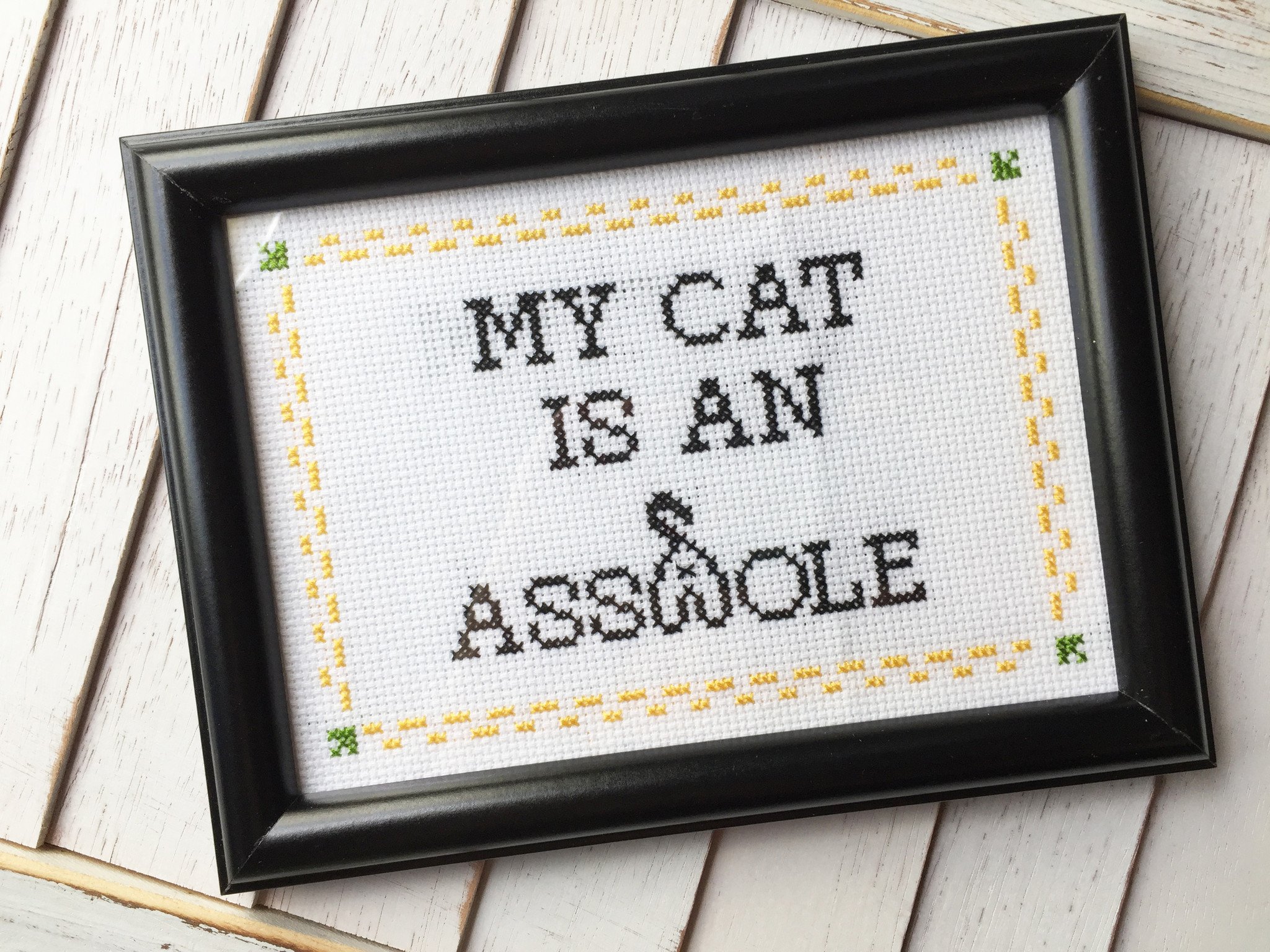 My Cat is an A**hole Counted Cross Stitch DIY Kit with colorful threads, Aida fabric, and a wooden hoop.