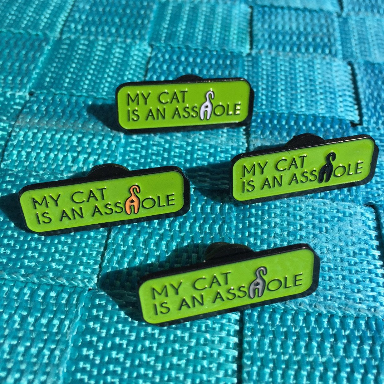 My Cat is an A**hole Soft Enamel Pin featuring a playful cat butt design in vibrant colors, measuring 1.25 inches.