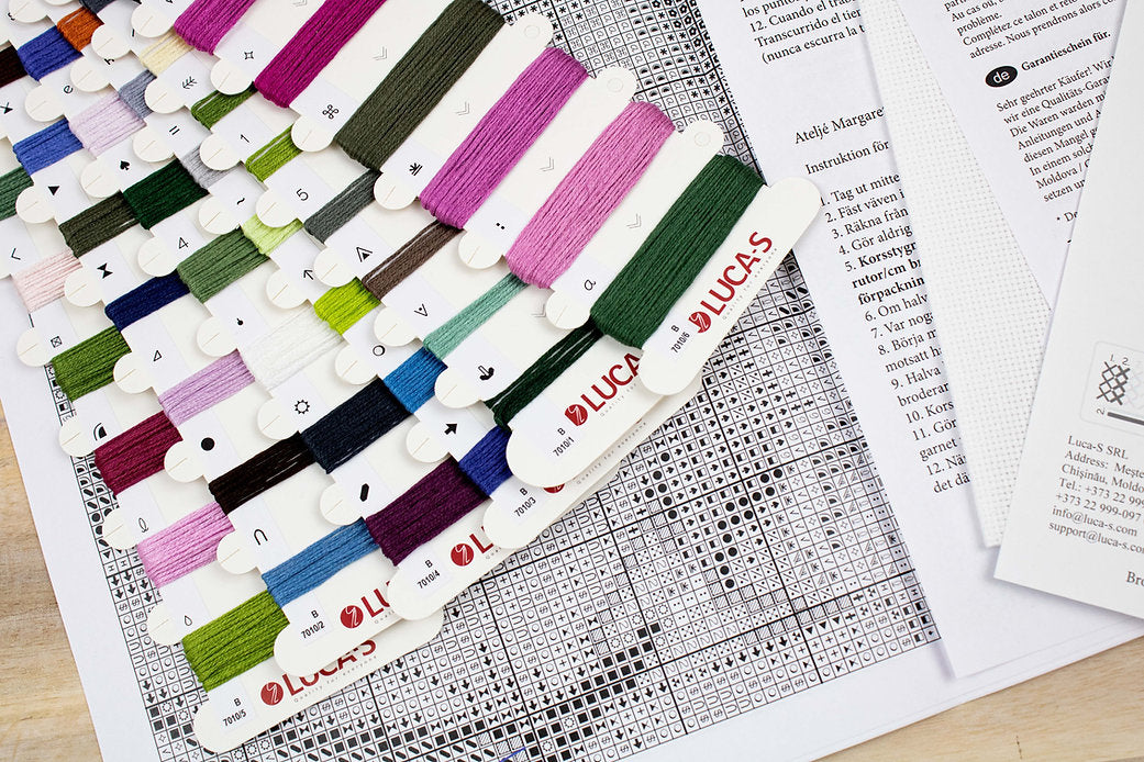 Nature's Poetry B7010L Counted Cross-Stitch Kit with Aida canvas, needle, and colorful threads displayed on a table.