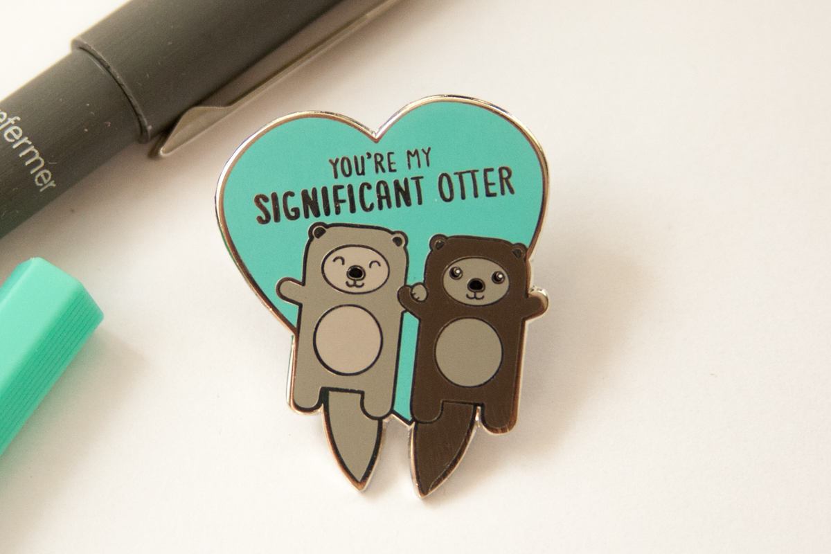 Otters Holding Hands Hard Enamel Pin featuring two otters with the text 'You're My Significant Otter' in a playful design.