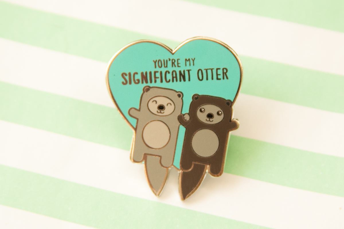 Otters Holding Hands Hard Enamel Pin featuring two otters with the text 'You're My Significant Otter' in a playful design.