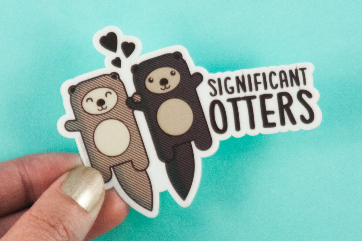Vinyl sticker featuring two cute otters holding hands with the text 'Significant Otters'. Perfect for personalizing items.