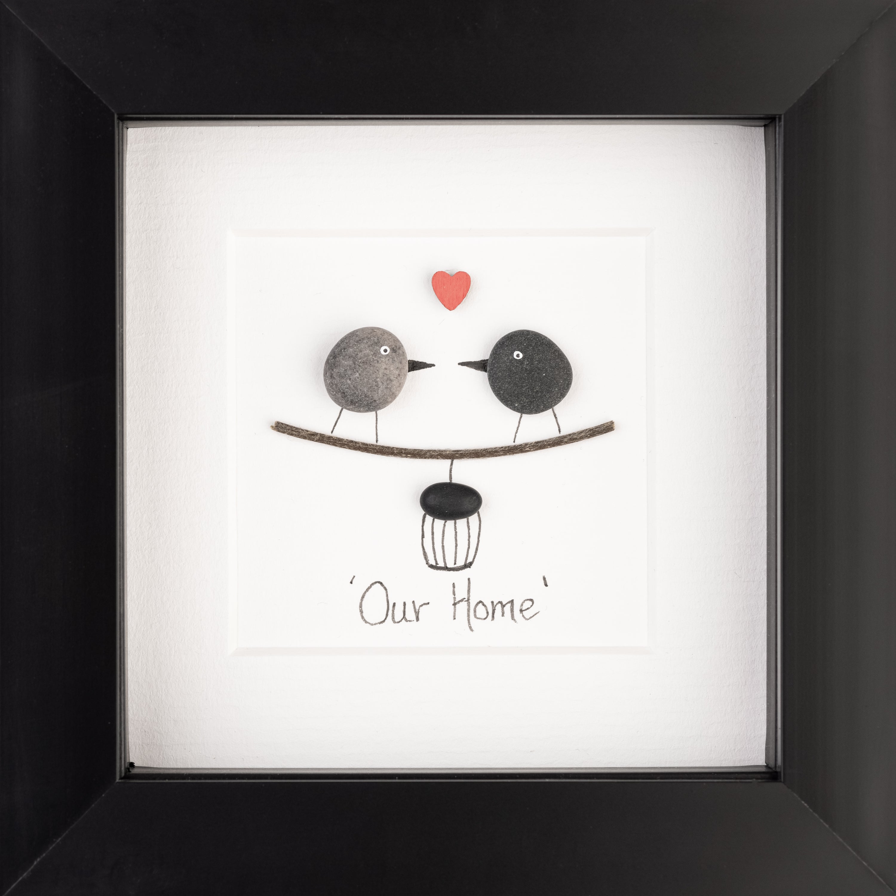 A beautifully framed pebble art picture depicting a cozy home scene, featuring natural pebbles arranged artistically.