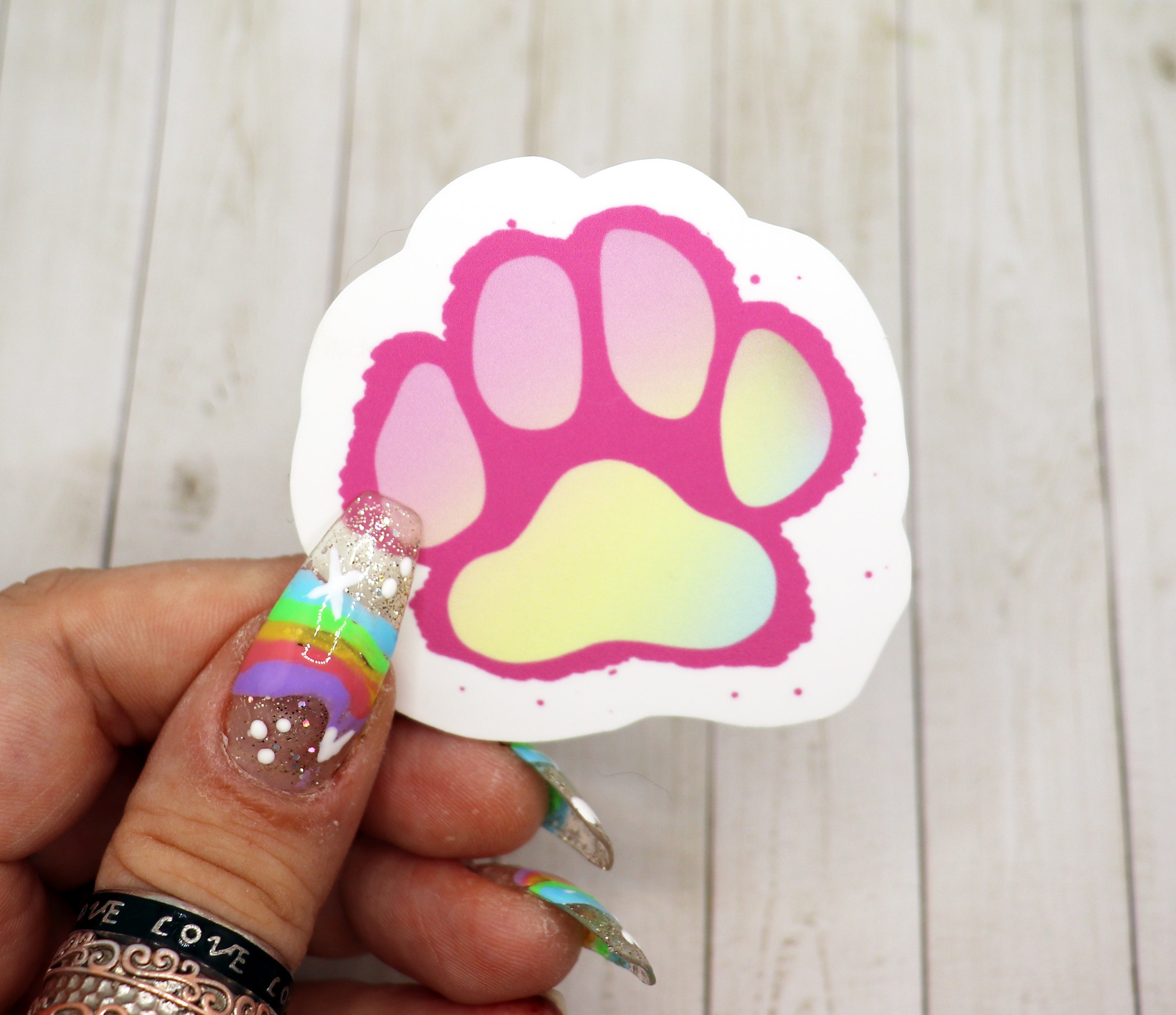 A pastel-colored vinyl sticker featuring a cute paw print design, perfect for personalizing various items.
