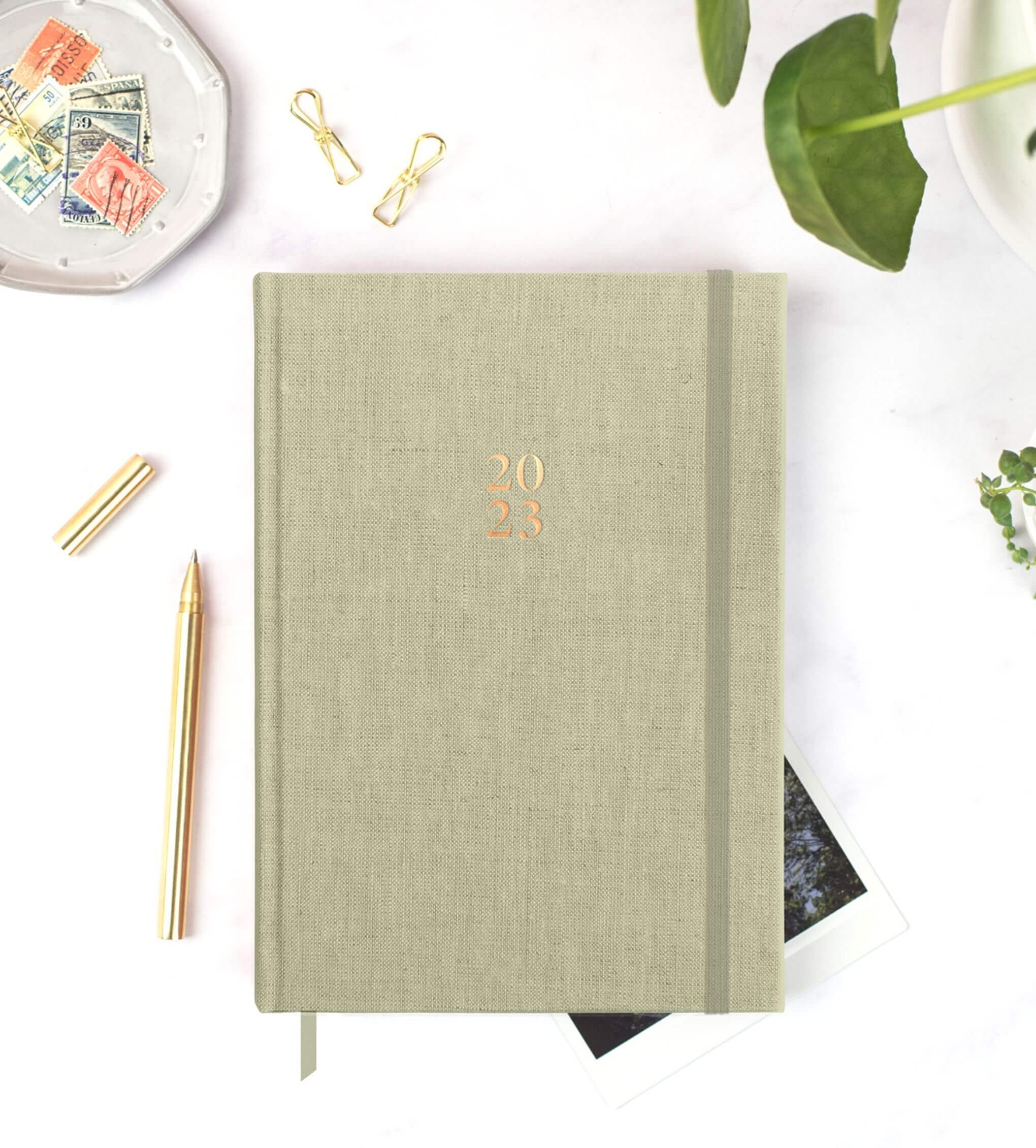 Ponderlily® Weekly Planner 2023 in Sage with soft fabric cover and foiled copper lettering, showcasing its elegant design.