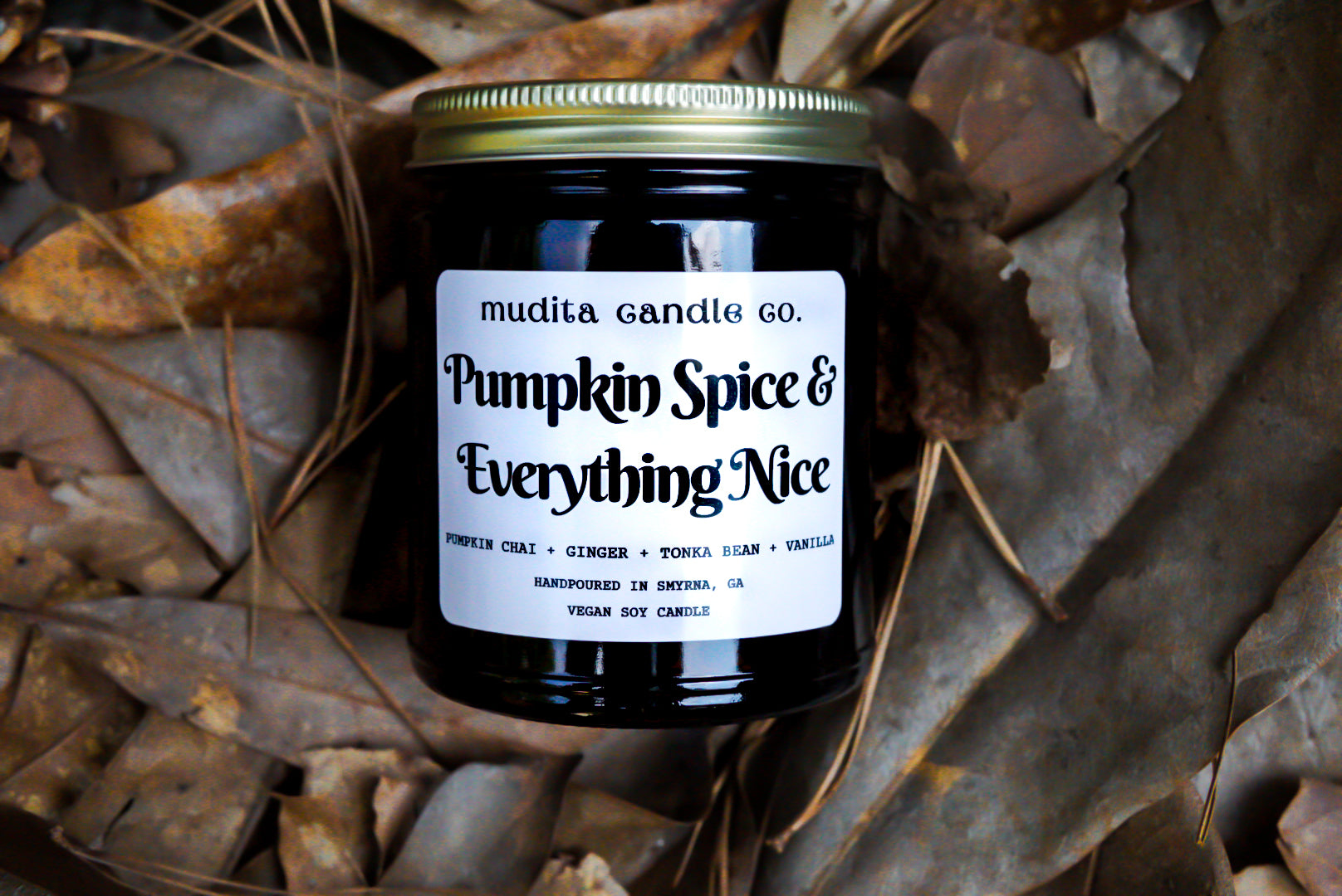 A 9oz amber glass jar candle with a gold metal lid, featuring a warm pumpkin spice scent blend.