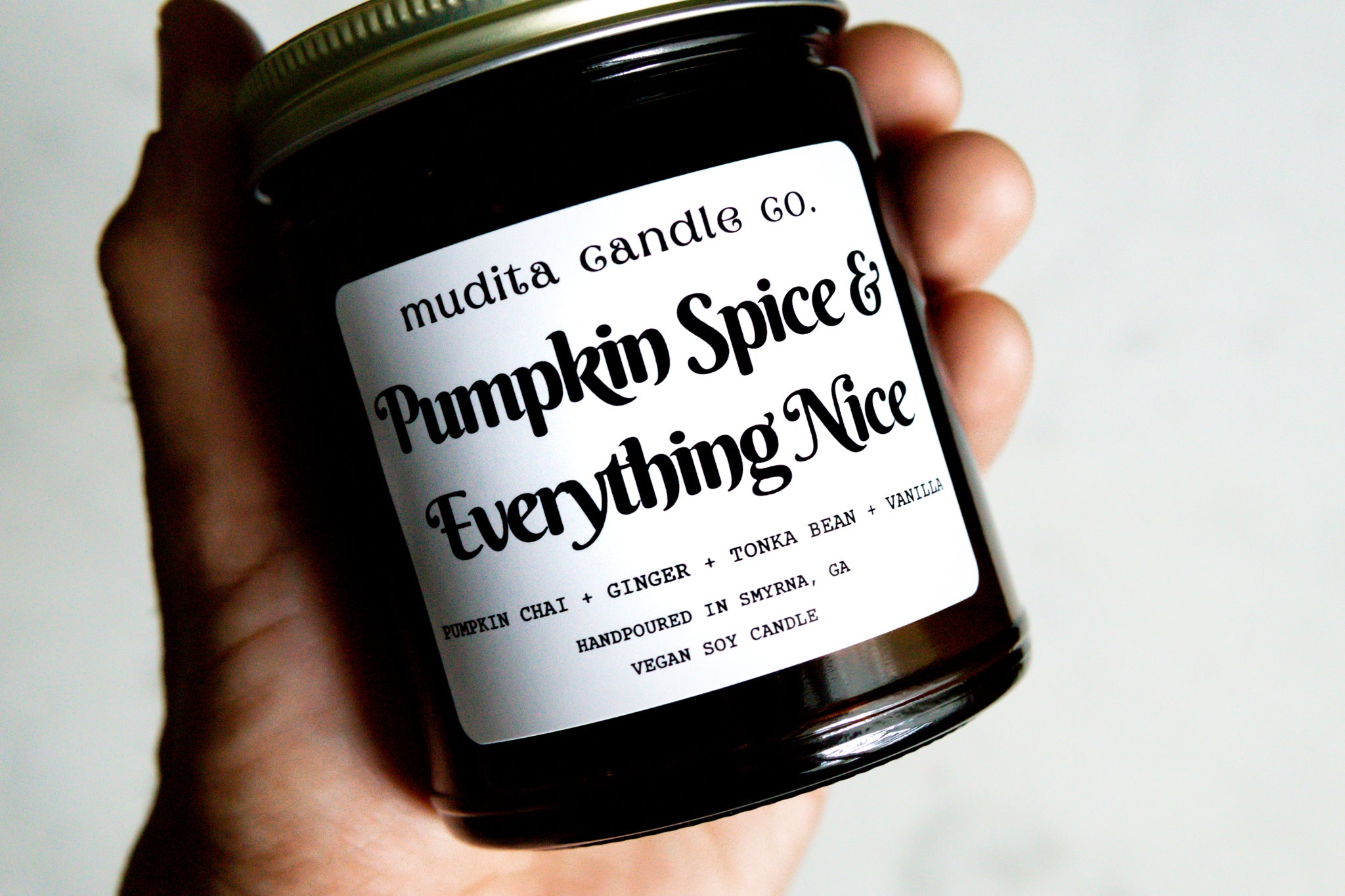 A 9oz amber glass jar candle with a gold metal lid, featuring a warm pumpkin spice scent blend.