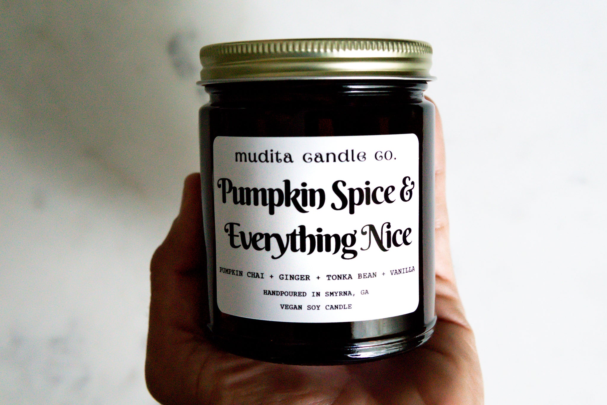A 9oz amber glass jar candle with a gold metal lid, featuring a warm pumpkin spice scent blend.