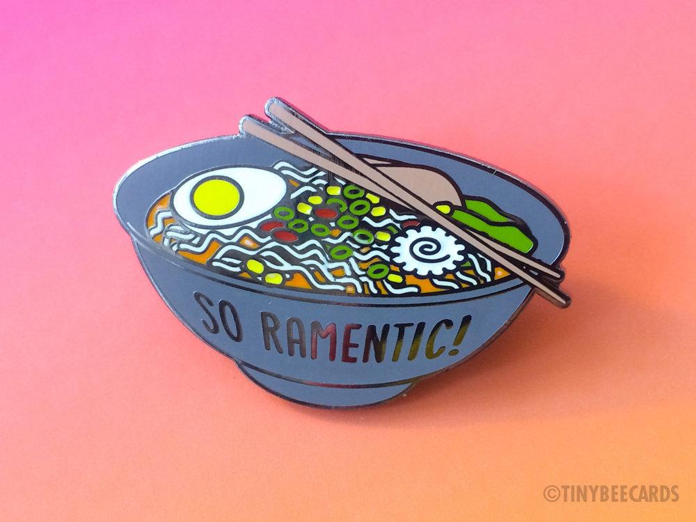 A colorful hard enamel pin featuring a bowl of ramen with the text 'So Ramentic' in a playful font.