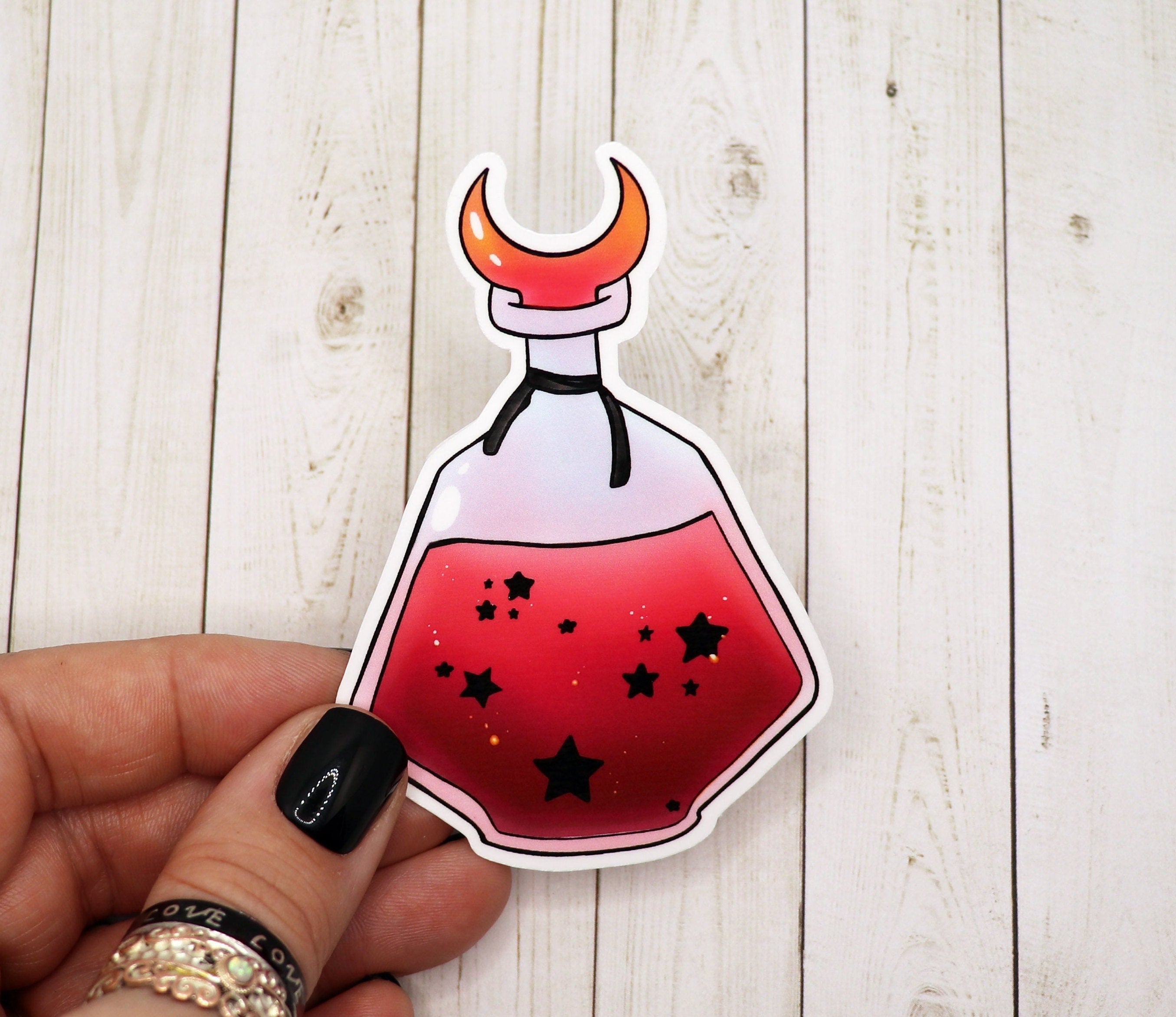 A vibrant red and black star potion bottle sticker on a white background, showcasing its intricate design and matte finish.