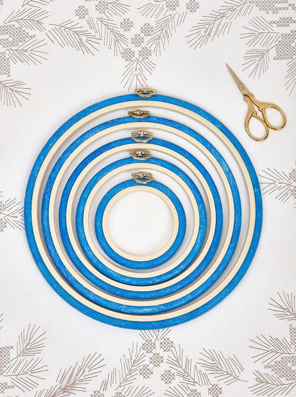 Nurge 230-2 Blue Flexi Hoop, a round embroidery tool with a rubberised wood-grained outer and decorative hook for hanging finished projects.