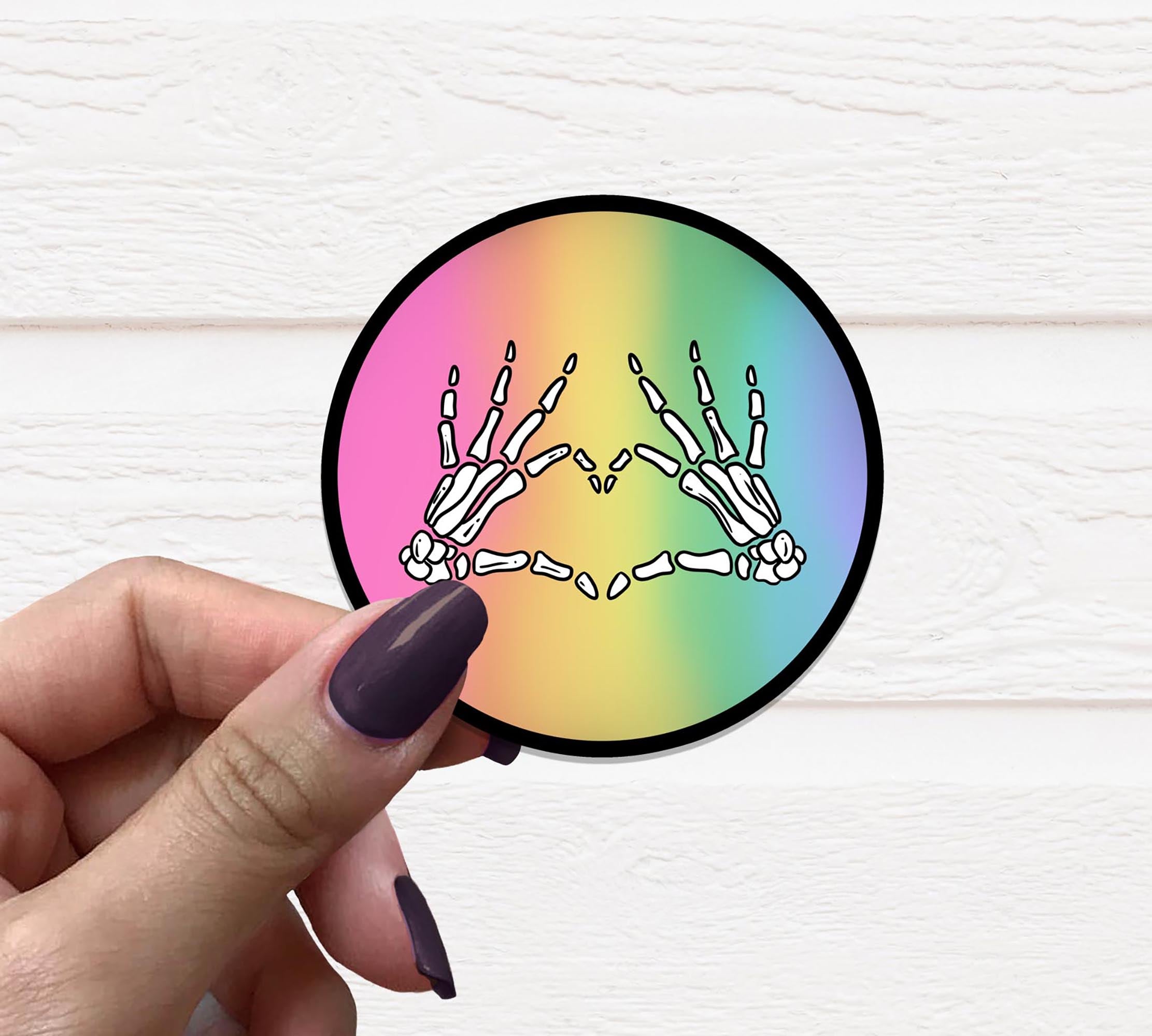 Skeleton Love Hands Sticker on a matte vinyl surface, showcasing its unique design and vibrant colors.
