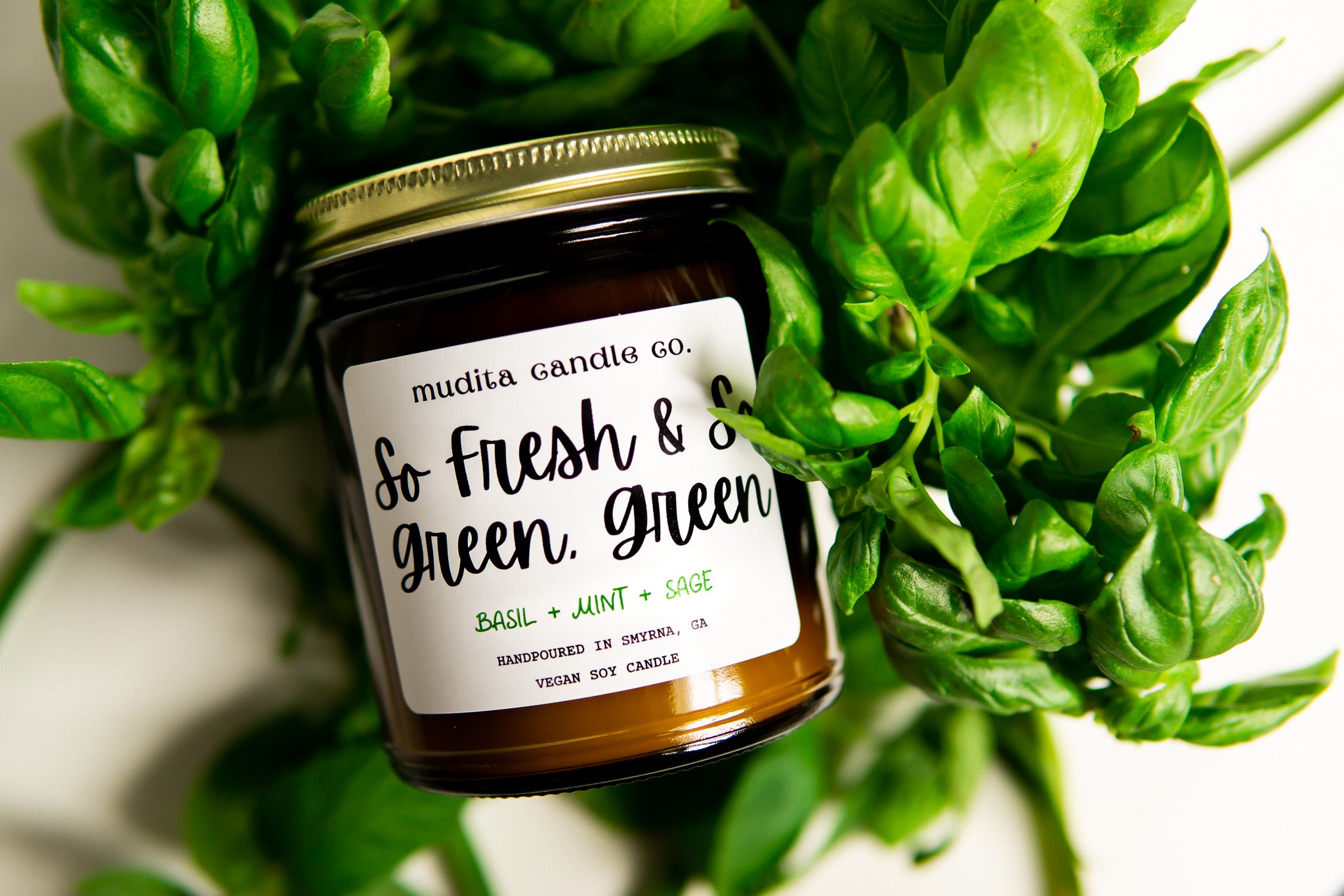 So Fresh & So Green, Green 9oz Soy Candle in amber glass jar with gold lid, featuring fresh basil, mint, and sage scent.