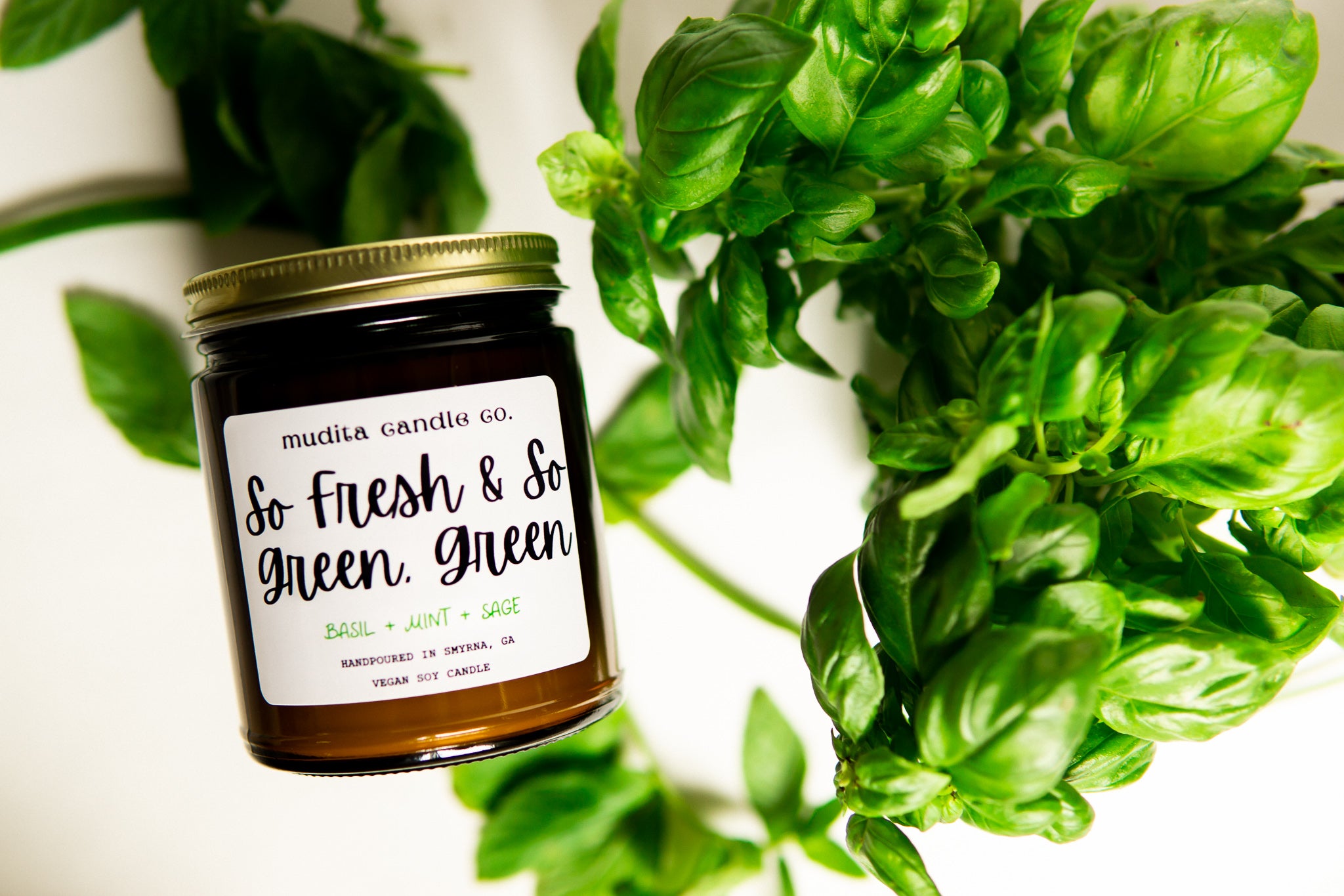 So Fresh & So Green, Green 9oz Soy Candle in amber glass jar with gold lid, featuring fresh basil, mint, and sage scent.