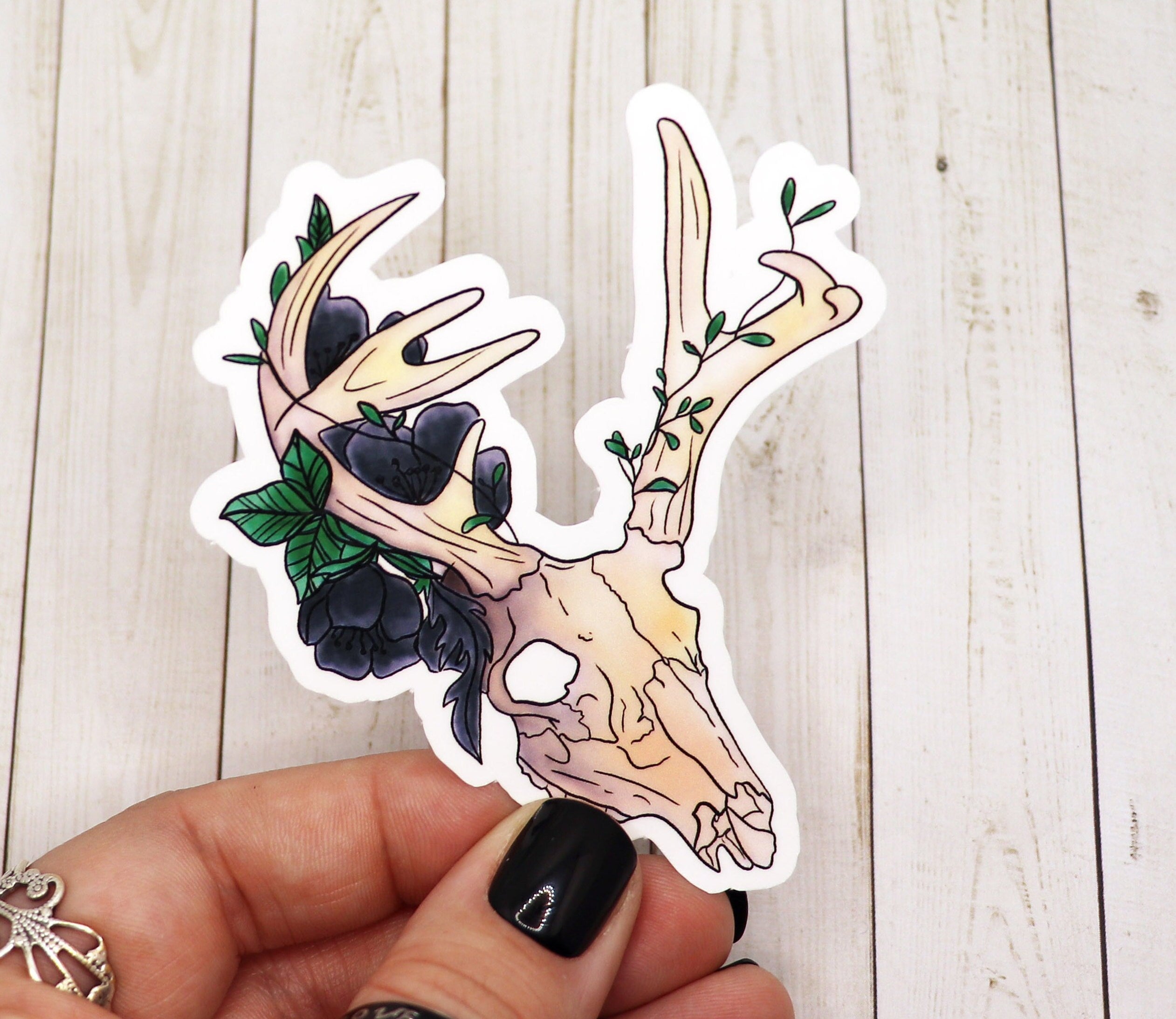 A detailed sticker featuring a stag skull surrounded by black roses, printed on matte vinyl.