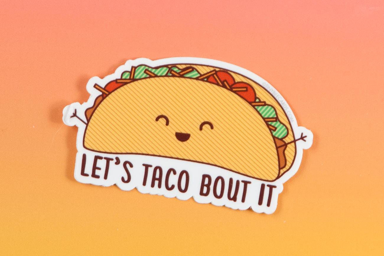 A colorful vinyl sticker featuring a happy taco illustration with the text 'Taco Bout It!' perfect for personalizing items.