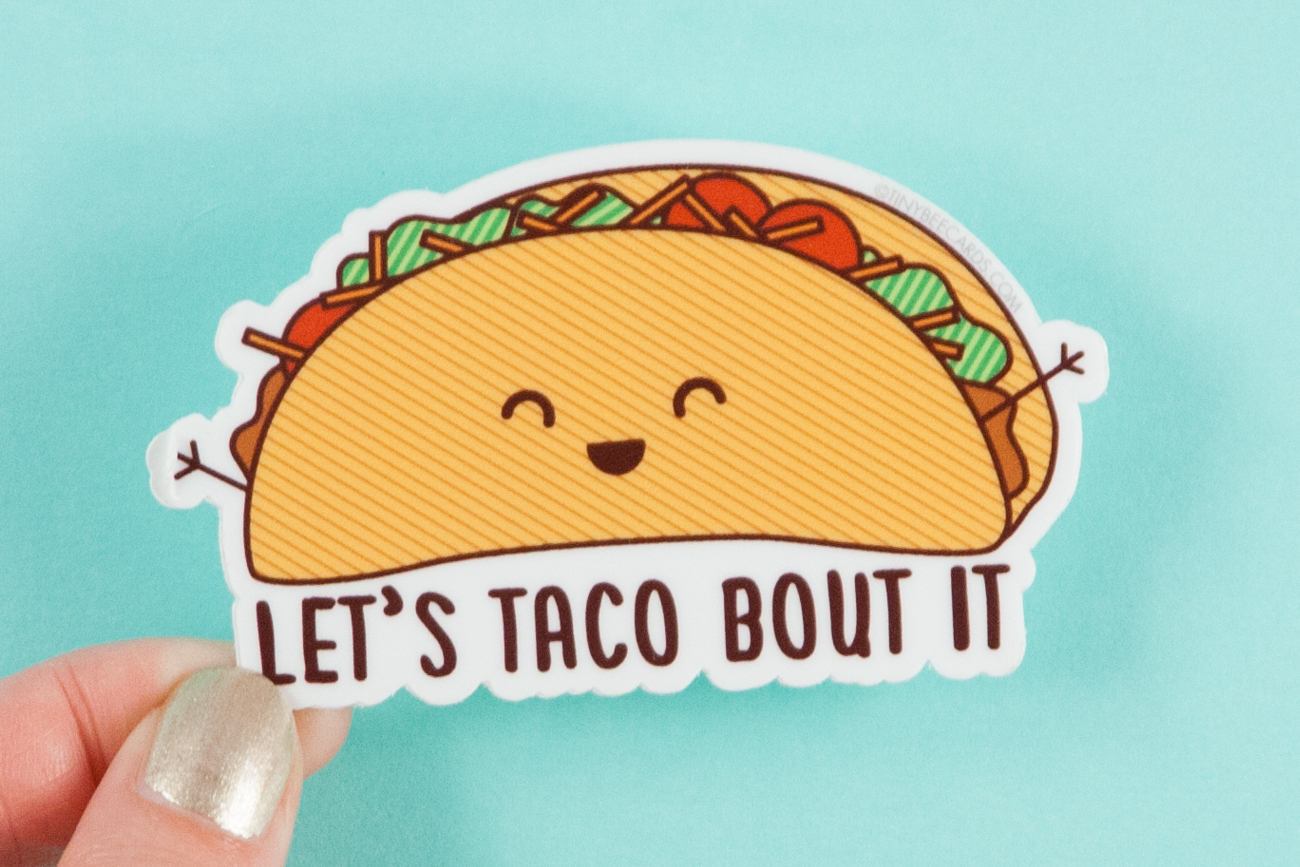 A colorful vinyl sticker featuring a happy taco illustration with the text 'Taco Bout It!' perfect for personalizing items.