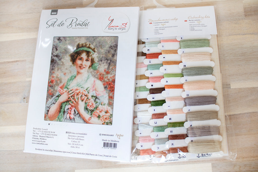 The Girl with Roses B553L Counted Cross-Stitch Kit featuring colorful threads, Aida canvas, and a needle.