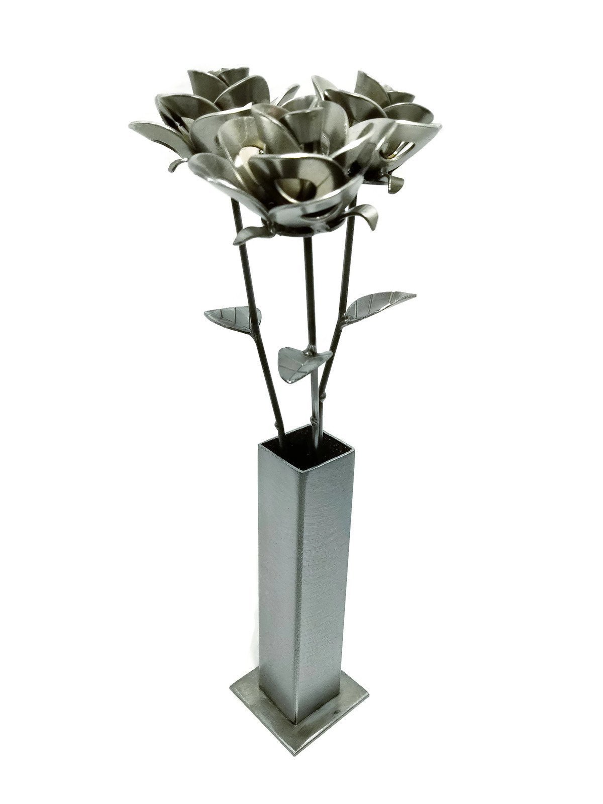 Three handcrafted metal roses in a rustic vase, made from recycled materials, showcasing unique welded designs and a shiny lacquer finish.
