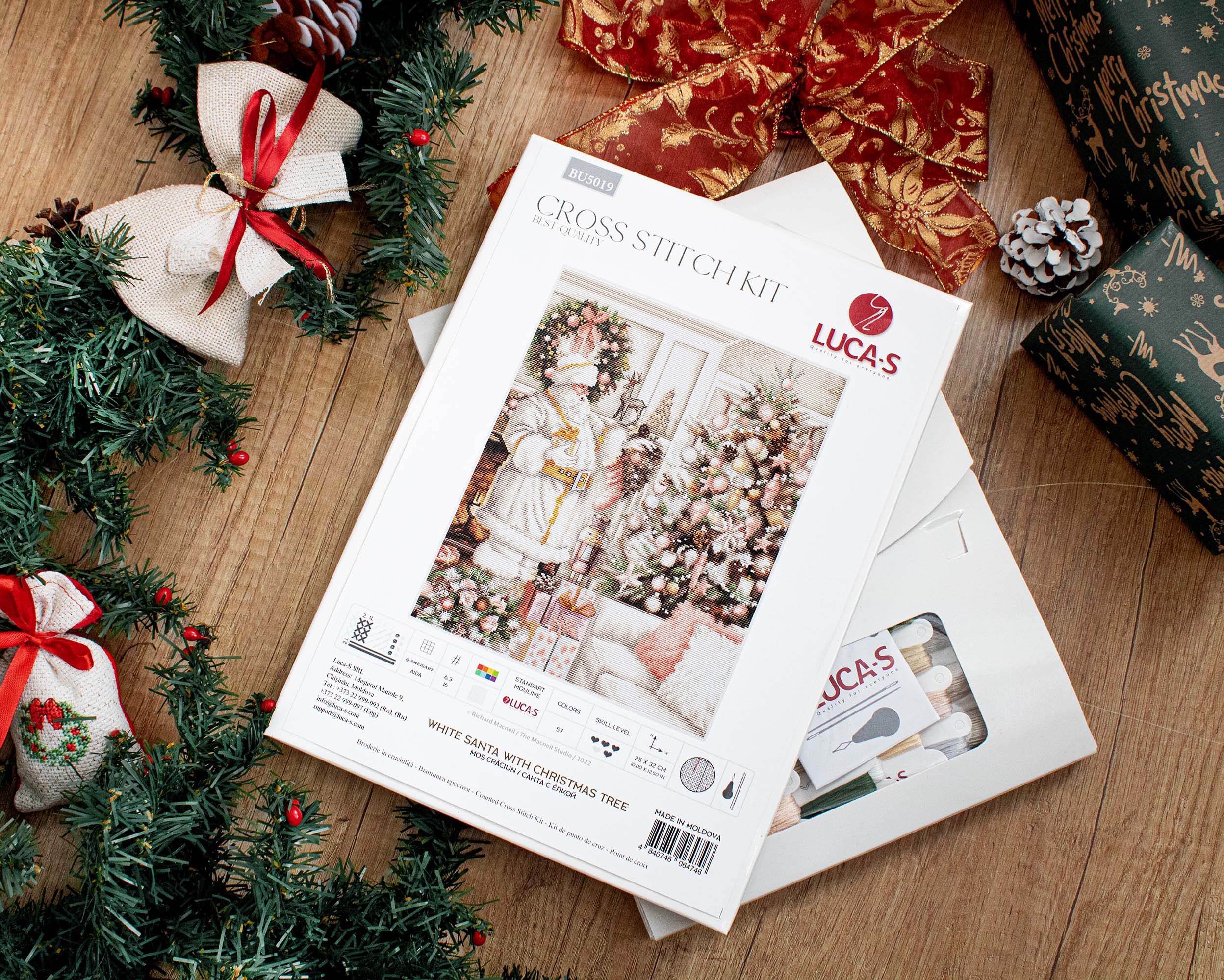 A counted cross-stitch kit featuring a white Santa Claus with a Christmas tree, including Aida canvas, colorful threads, and a needle.