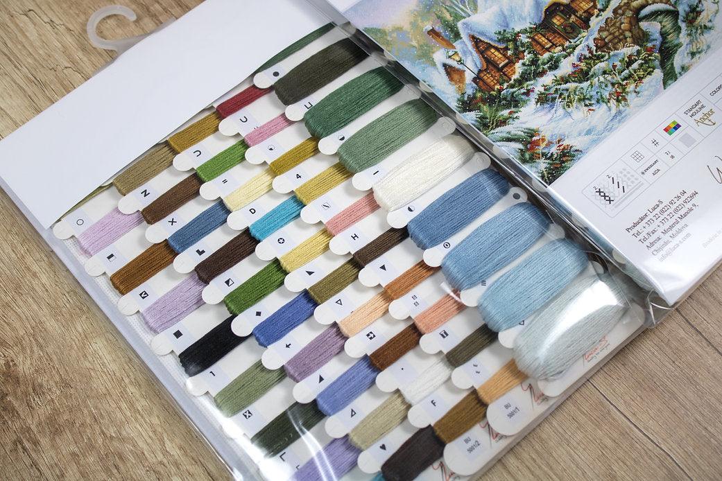 Winter landscape counted cross-stitch kit featuring Aida canvas, vibrant threads, and a needle for crafting.