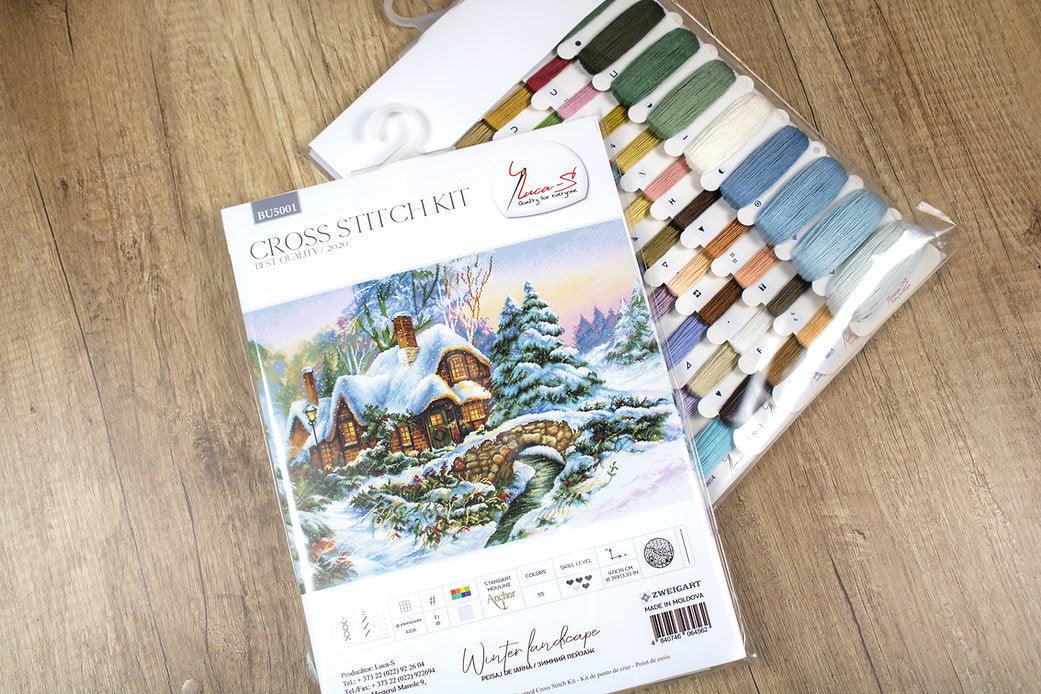 Winter landscape counted cross-stitch kit featuring Aida canvas, vibrant threads, and a needle for crafting.