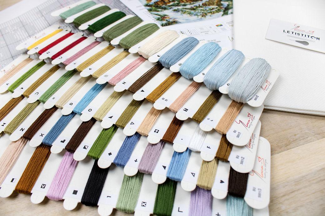 Winter landscape counted cross-stitch kit featuring Aida canvas, vibrant threads, and a needle for crafting.