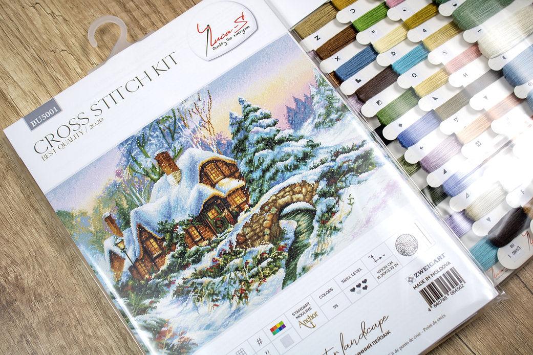 Winter landscape counted cross-stitch kit featuring Aida canvas, vibrant threads, and a needle for crafting.