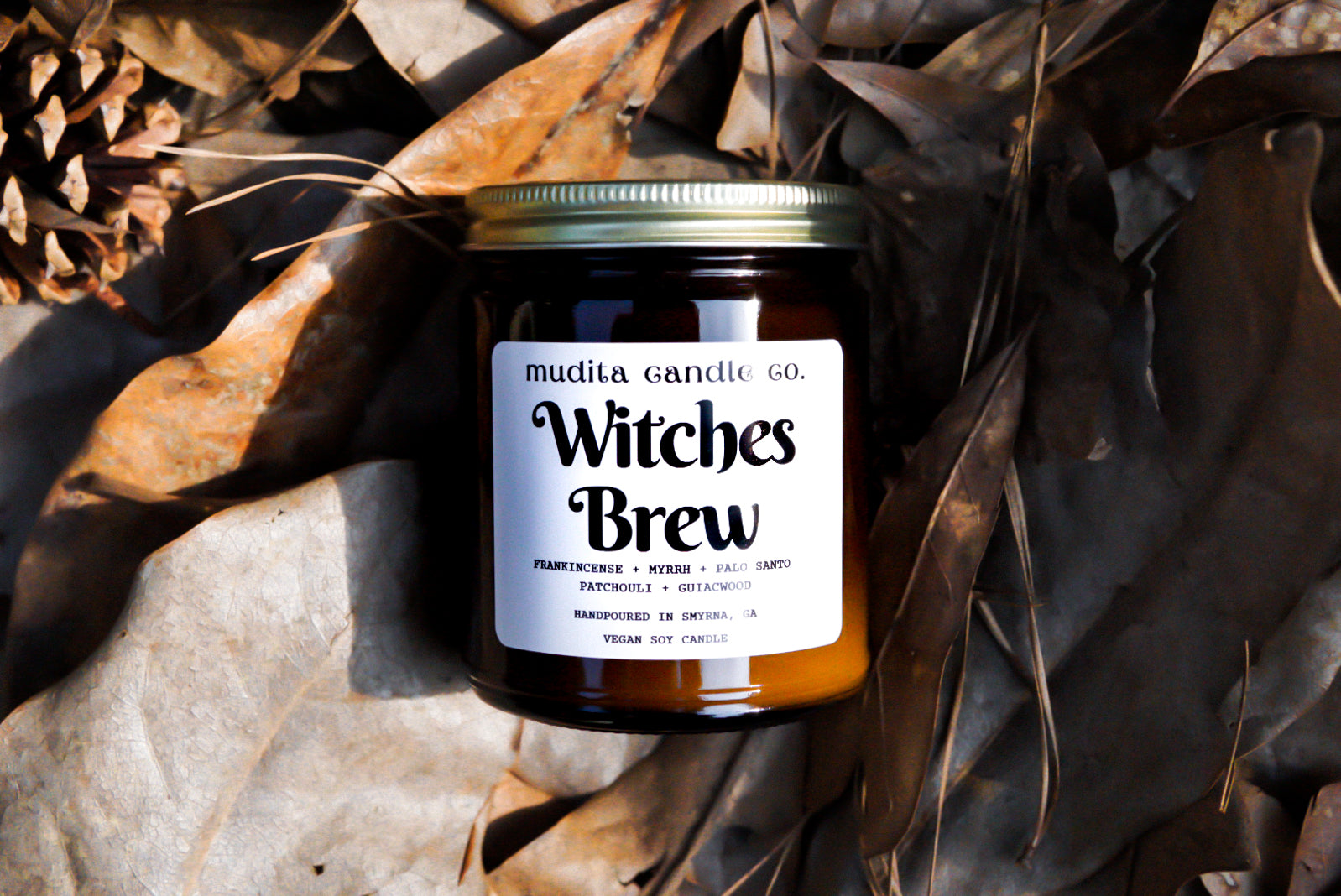Witches Brew candle in a 9oz amber glass jar with a gold lid, showcasing its natural soy wax and rich fragrance.
