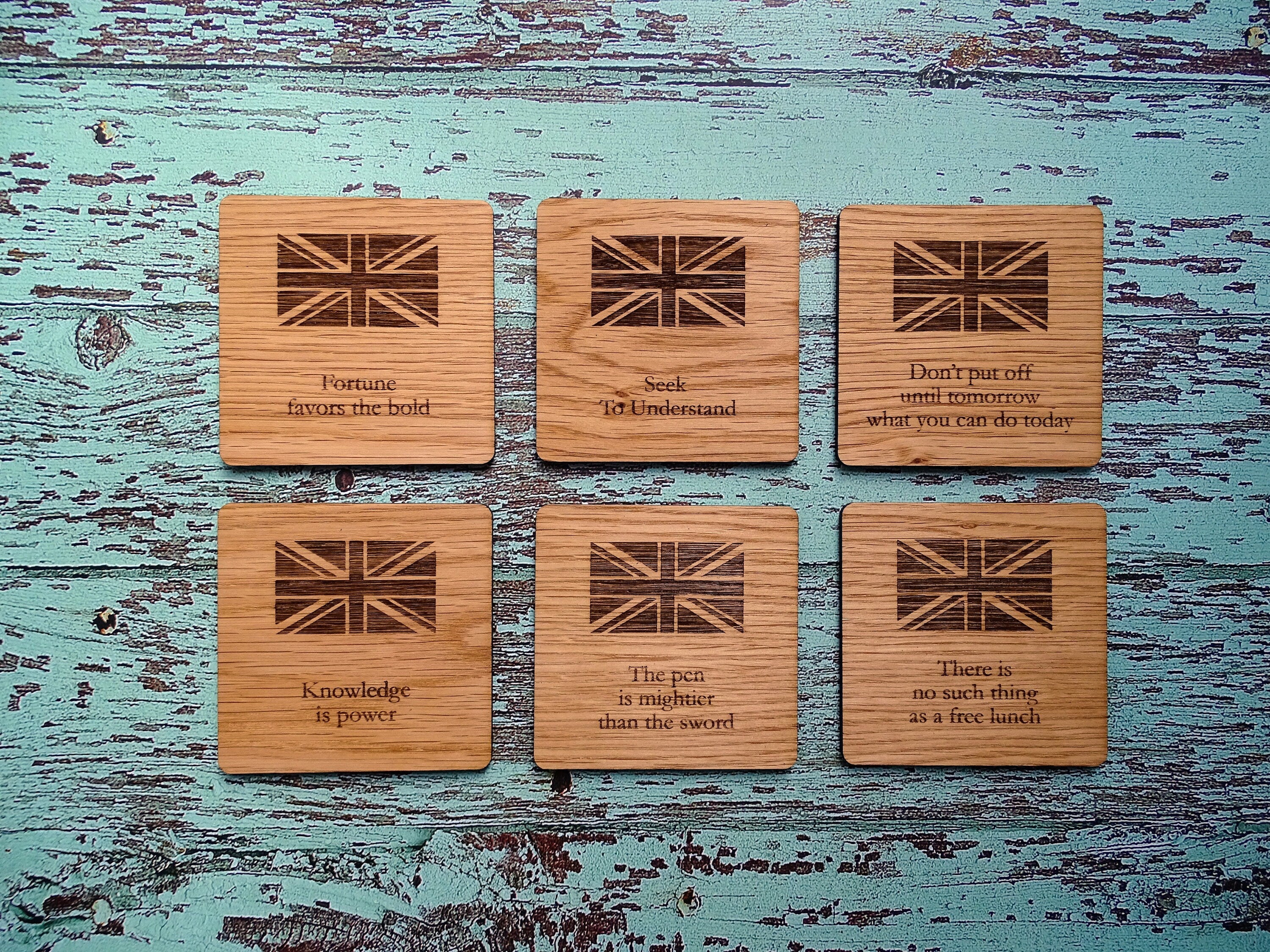 Set of six wooden coasters with English proverbs engraved, made from oak veneer, featuring rounded corners and a rustic finish.