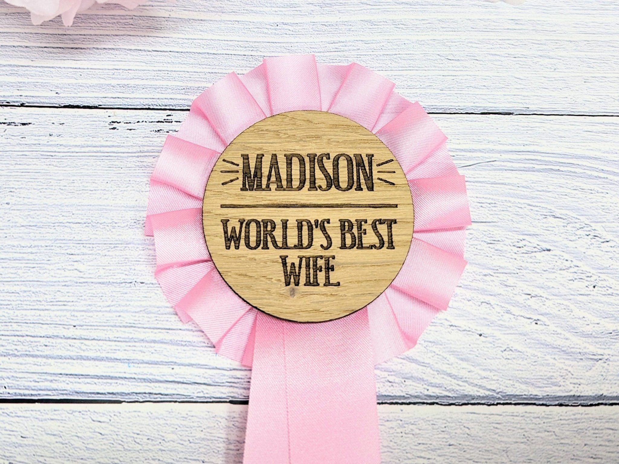 Personalised pink wooden rosette with 'World's Best Wife' text, handcrafted from oak veneered MDF, perfect for gifting.