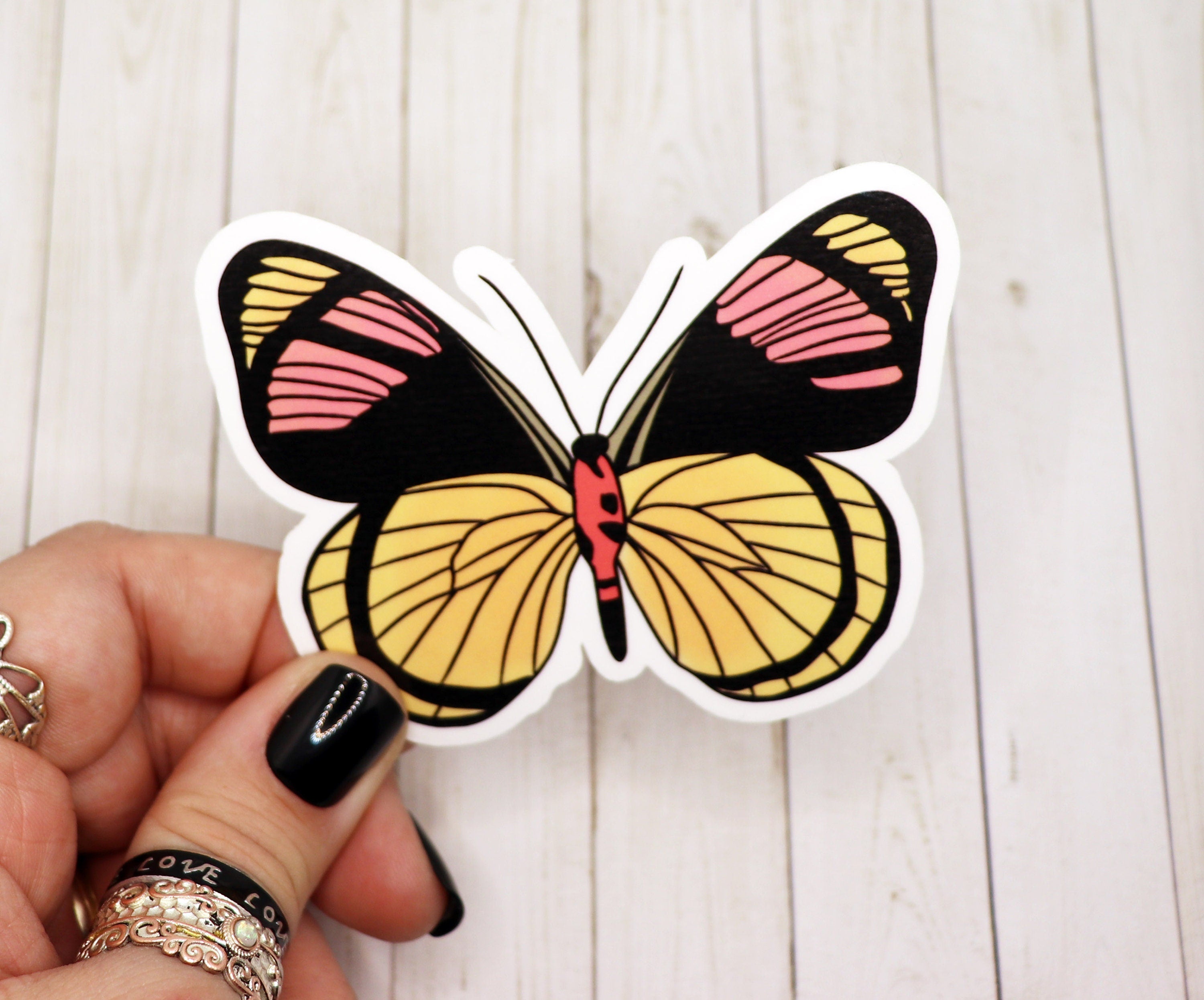 A collection of vibrant yellow and pink butterfly stickers on a white background, showcasing their intricate designs and matte finish.