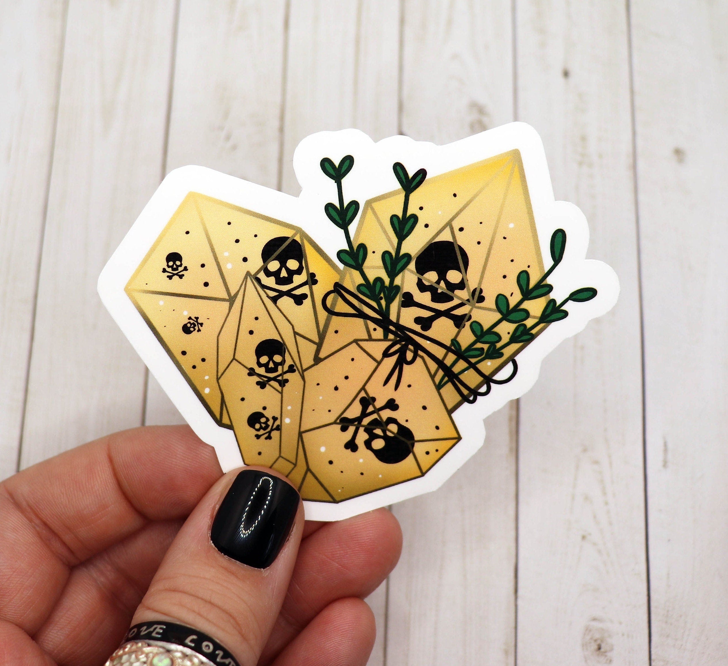 A vibrant yellow crystal sticker featuring bold black skulls, perfect for personalizing various items.