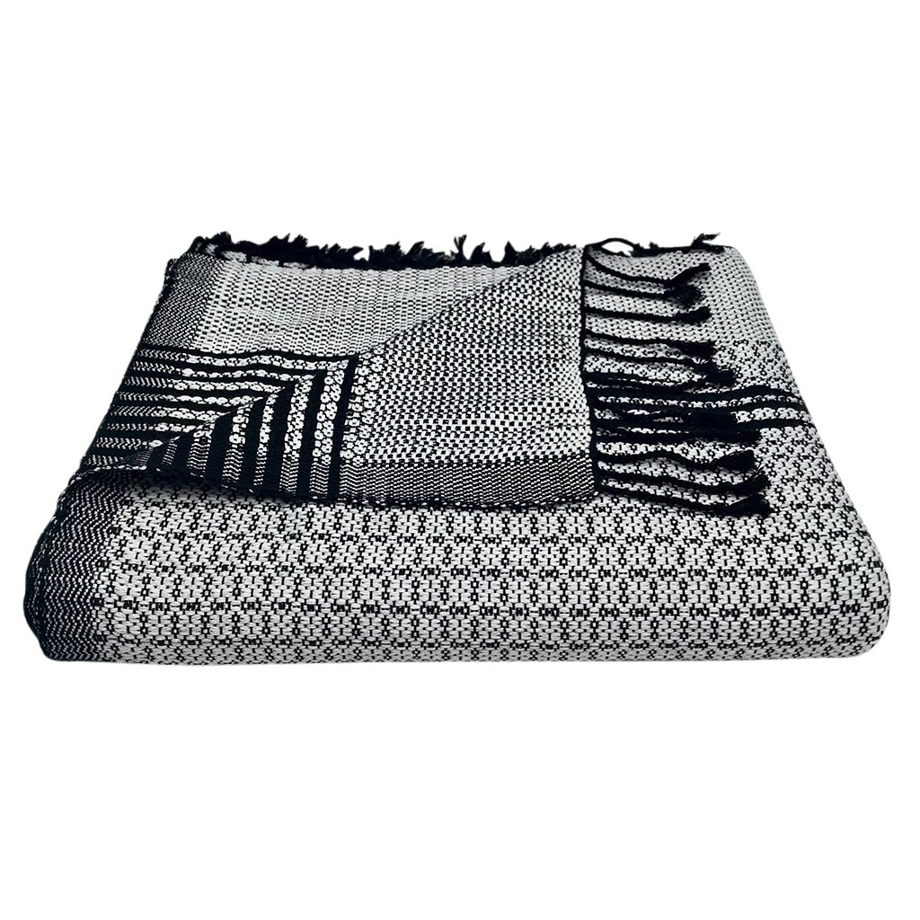 A luxurious silver gray and black tapestry throw made from organic cotton, featuring intricate flower patterns and hand-knotted fringe ends.