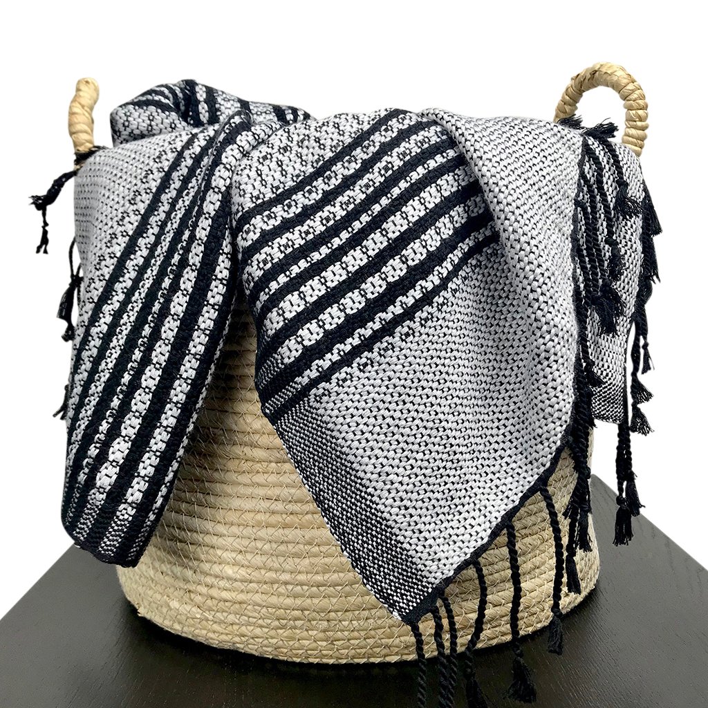 A luxurious silver gray and black tapestry throw made from organic cotton, featuring intricate flower patterns and hand-knotted fringe ends.