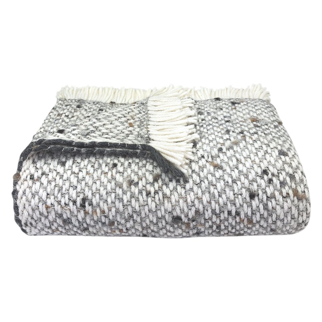 Chunky gray weave alpaca throw blanket draped elegantly on a sofa, showcasing its soft texture and neutral colors.